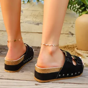 Detail view of black platform sandals with silver studs and metal buckles on a model.