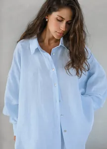 Primo piano di camicia azzurra oversize in lino e cotone con delicati bottoni bianchi.