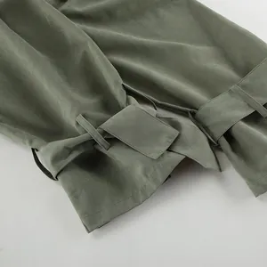 Detail of olive green trench coat cuffs with adjustable strap and buckle closure