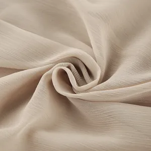 Detail view of soft khaki chiffon fabric with elegant crinkle texture for summer dresses