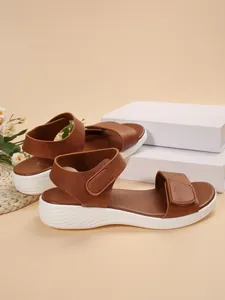Detailed side view of brown wedge sandals with white soles on display blocks
