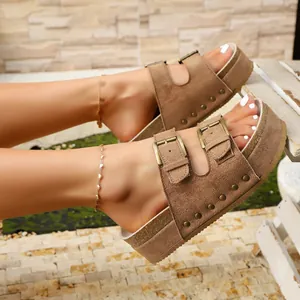 Close-up of brown suede platform sandals with metal buckles and rivet details