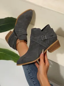 Close-up showing the cross straps and buckle detail on grey pointed-toe Chelsea boots