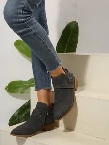 Detailed side view of grey pointed-toe ankle boots with cross straps and side zipper