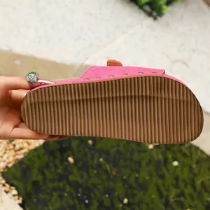 Detailed view of the anti-slip brown ripple sole of a pink suede platform slipper