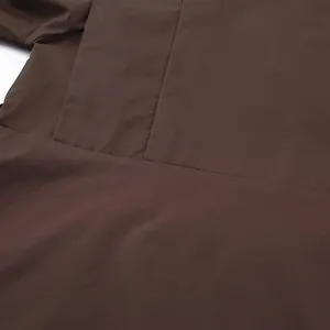 Detail shot showing the fine stitching and brown fabric texture of a women's trench coat