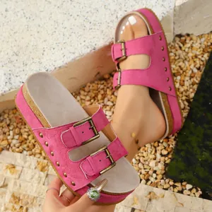 Close-up detail of vibrant pink platform cork sandals with gold metal buckles and studs