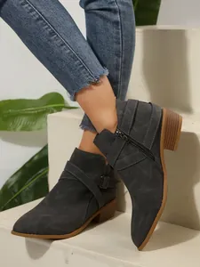 Detailed side view of grey pointed-toe ankle boots featuring cross straps and side zipper