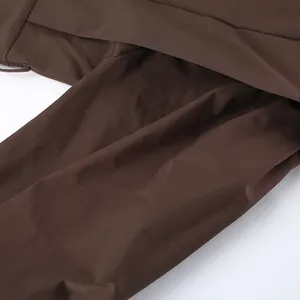 Close-up detail showing the texture and layered flap design of this dark brown trench coat