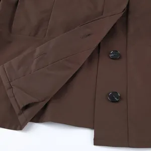 Nahaufnahme von schwarzen Knöpfen und hochwertigen Nähten auf braunem Trenchcoat