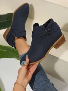 Detailed side view of blue pointed-toe Chelsea boots with cross-strap and buckle.