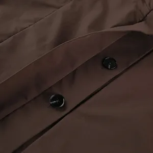 Nahaufnahme makro-detail glänzender schwarzer knöpfe auf braunem grabenmantelstoff