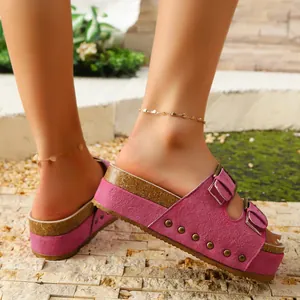Detail view of pink suede platform sandals with gold studs and adjustable metal buckles