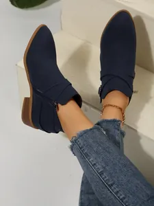Close-up of navy blue pointed-toe Chelsea boots with cross straps and side zipper