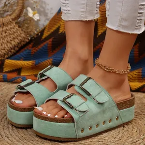Detailed view of mint green suede platform sandals with gold rivets and double buckles.