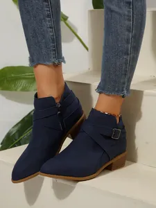 Navy blue pointed-toe ankle boots with cross straps and side zipper on stairs
