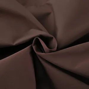 Close-up of premium chocolate brown trench coat fabric displaying elegant texture and drape