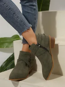 Detail of olive green pointed-toe ankle boots with cross straps and side zipper