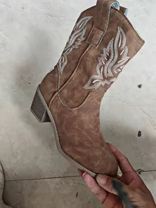 Détail de botte de cowboy marron avec broderie d'ailes blanches et talon carré