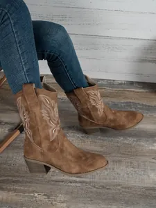 Détail de bottes de cowboy marron avec broderie blanche et talons blocs épais