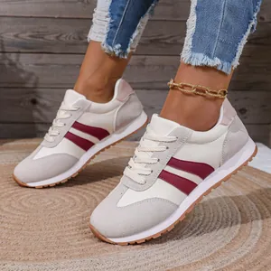 Vista laterale di sneakers da corsa leggere e traspiranti con strisce bordeaux da donna