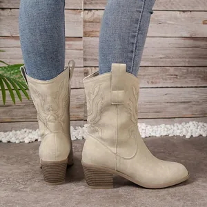 Détail de la broderie complexe et du talon bloc de ces bottes western de couleur crème.