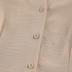 Primer plano de tela texturizada rugosa caqui y detalles de botones redondos en un vestido