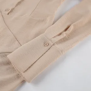 Detalle de vestido caqui en tela texturizada que muestra el puño abotonado y diseño plisado.
