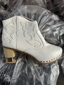 Side view of white embroidered fashion ankle boot featuring rivets and clear acrylic heel