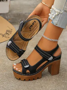 Side view of black platform sandals with thick block heels and white stitching detail
