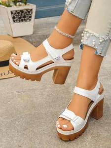 Detailed close-up of white platform high heel sandals with velcro straps worn by a model