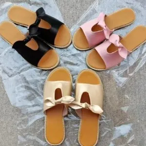 Three pairs of flat bow sandals in black, pink, and gold displayed on a simple background