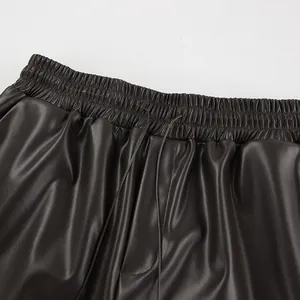 Détail en gros plan de la taille élastique et des cordons sur un pantalon en simili cuir mat