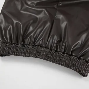 Détail de la texture et de l'ourlet élastiqué d'un pantalon en similicuir mat à taille haute
