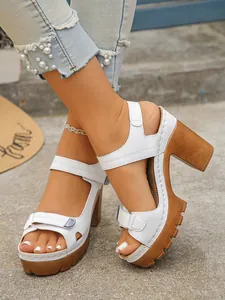 Close-up of white platform sandals with chunky textured soles worn with distressed pearl jeans.
