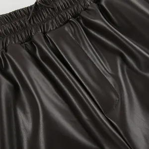 Gros plan d'un pantalon en similicuir mat marron foncé avec taille élastiquée.