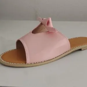 Close-up of pink flat slide sandal featuring a cute bow decoration on the strap
