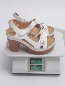 Detailed shot showing the weight of a white platform chunky heel sandal on a scale