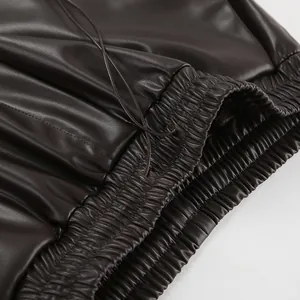 Gros plan sur la taille haute élastiquée d'un pantalon en similicuir marron foncé mat