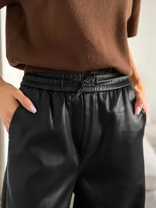 Détail du pantalon en simili cuir noir mat à taille haute avec cordon de serrage