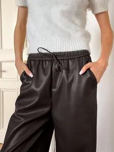 Gros plan d'un élégant pantalon en simili cuir mat gris avec taille haute à cordon.