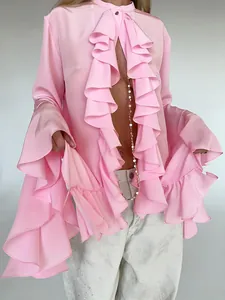 Detalle de elegante blusa de satén rosa con volantes en cascada y mangas acampanadas.