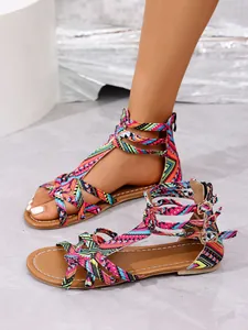 Detailed macro view of colorful Bohemian style flat Roman sandals with braided straps.