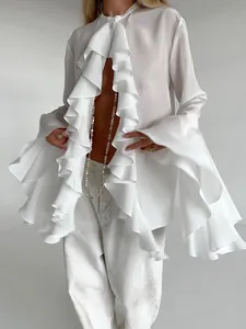 Detalle de blusa blanca de gasa con volantes elegantes y mangas acampanadas.