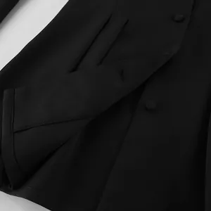 Detailansicht des Stoffes und des stoffbezogenen Knopfes an einem schwarzen Blazer.