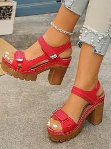 Detailed view of red platform sandals with chunky wooden heels and velcro strap.