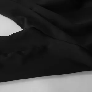 Close-up detail of black blazer fabric texture and precision stitching on ruched waist.