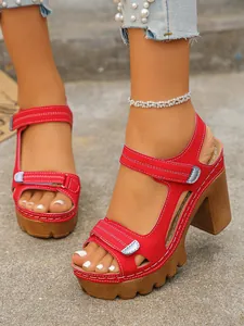 Close-up of red platform high-heel sandals with velcro straps and thick soles.