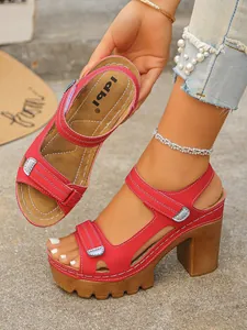 Close-up of red platform sandals with chunky wood-textured heels and white stitching
