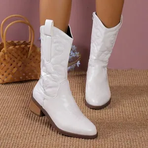 Close-up view of elegant white mid-calf cowboy boots featuring pointed toe and chunky heel.